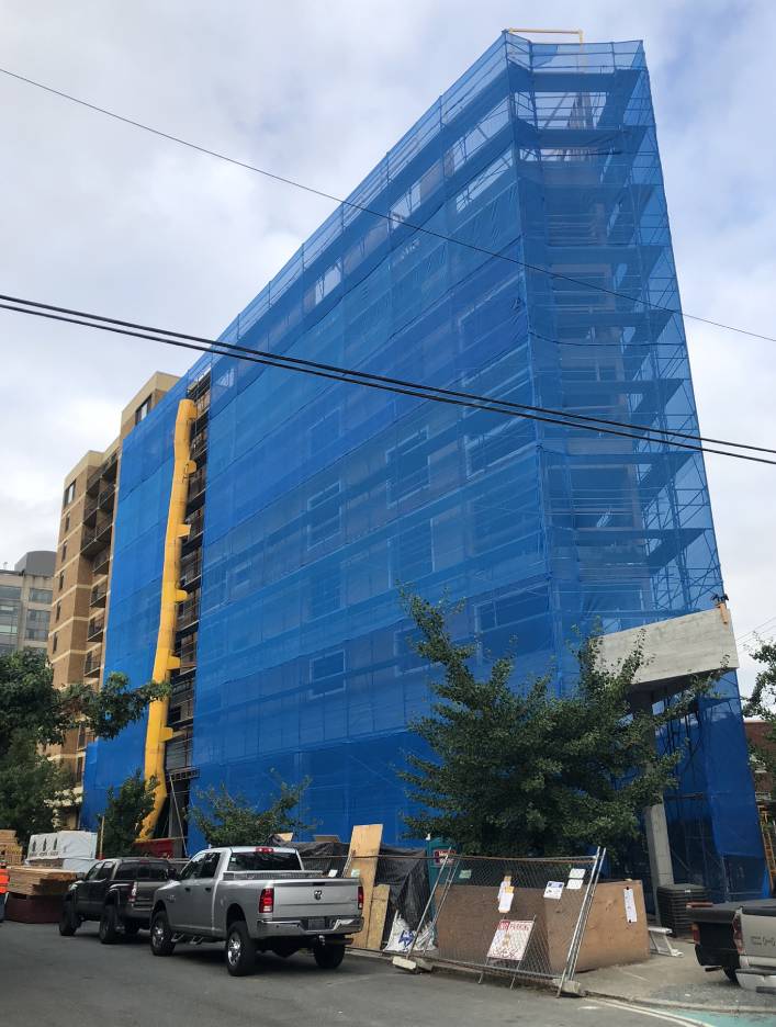 A blue building with a blue tarp in front of it, provided by Premier Scaffold, Inc.