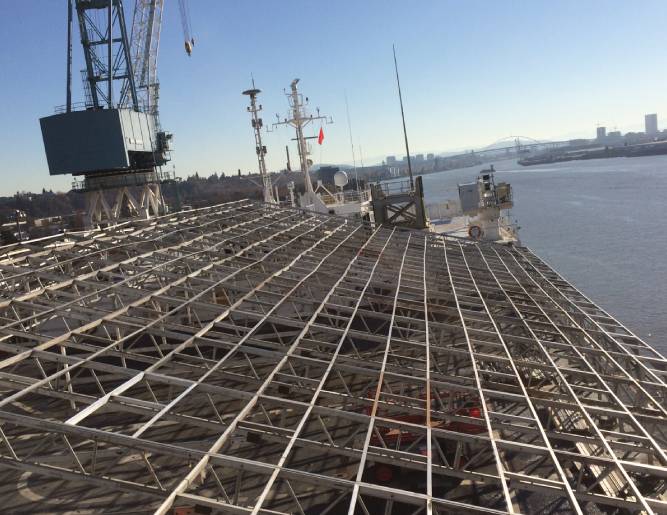 A steel structure on a ship with a crane in the background.